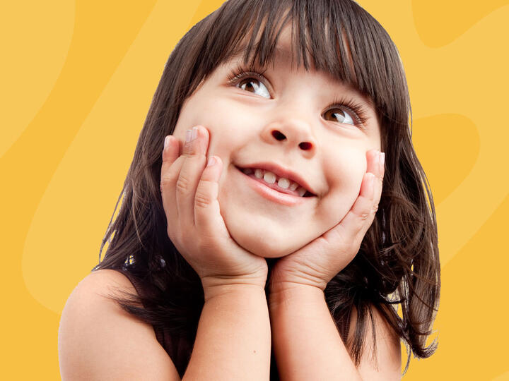 little girl smiling holding her face