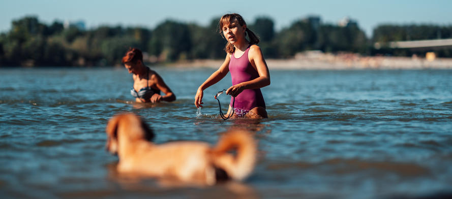 girl swimming in a river with her dog