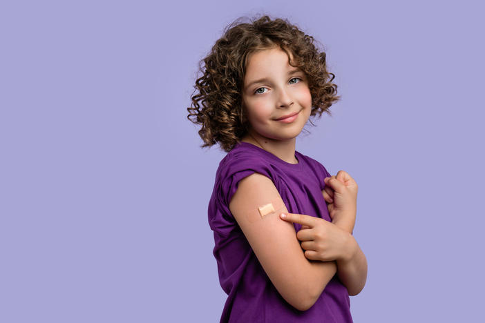 kid in purple with a vaccine bandage
