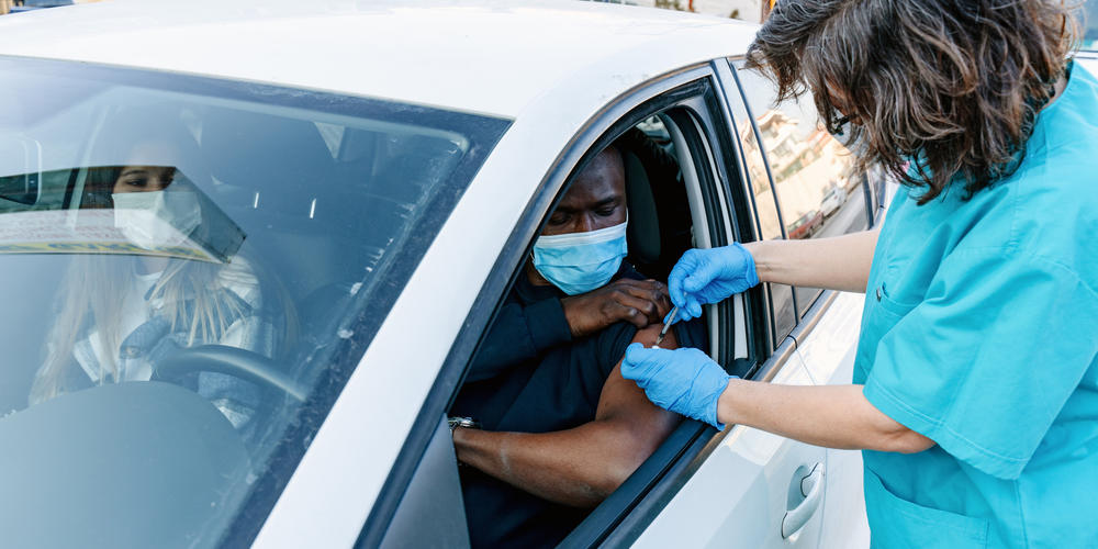 nurse giving vaccine to patient in a car